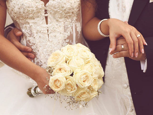 Detail of bride's roses bouquet and hands holding