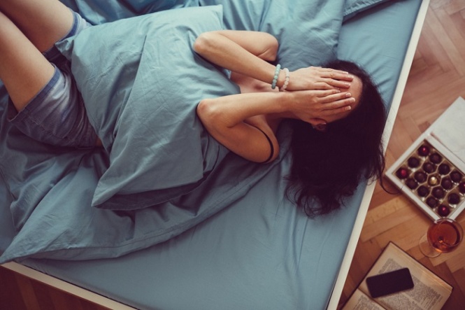 Depressed woman in bed with hands on face