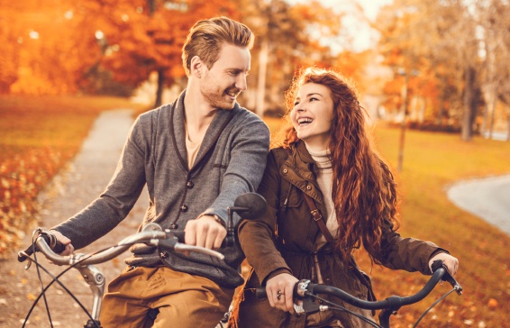Ginger couple talking on bicycles during autumn day.