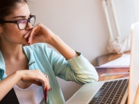 Young female blogger working at home.She sitting in her working room and typing something on laptop.Startup business.Looking worried.