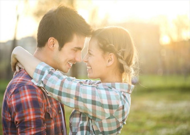Happy attractive heterosexual couple embracing in a park. Both Caucasian in casual clothing, about 20-25 years old