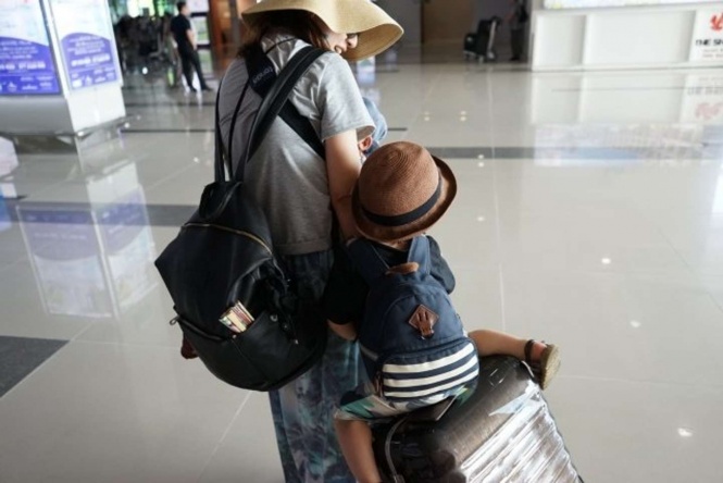 子供を抱えてのスーツケースの持ち運びは大変(画像はイメージ)
