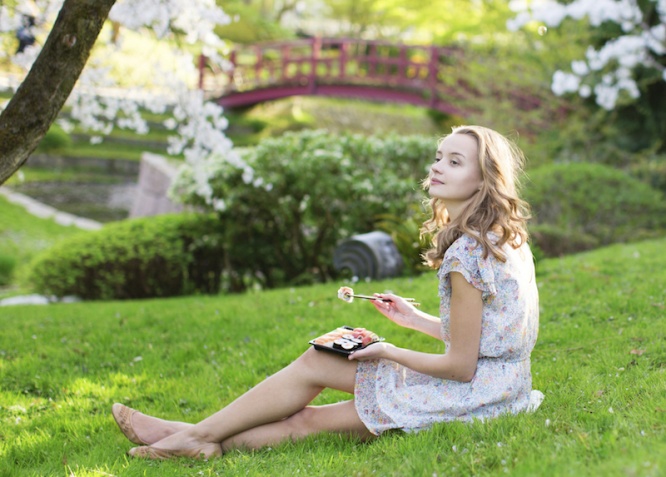 Young European woman eating sushi in Japanese park