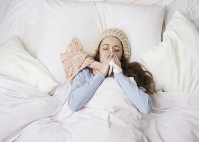 Sick woman with thermometer is lying in bed. She has cold, flu and high fever.