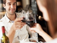 Smiling young man clinking glasses with his girlfriend while at dinner