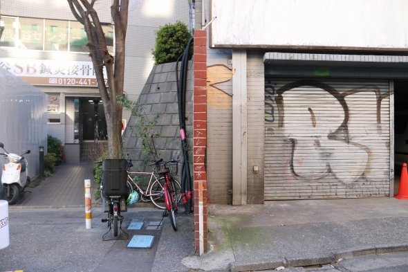 塀の右側が再開発エリアだが、左側では人が出入りする平凡な日常になっている