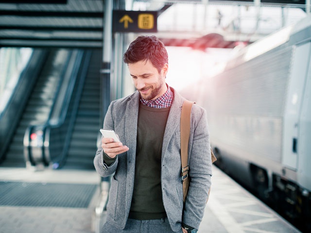 Businessman using mobile phone at train station