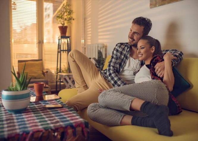 Happy couple sitting embraced in the living room and enjoying in their time together.