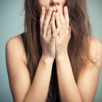 The woman touches finger-tips to the mouth