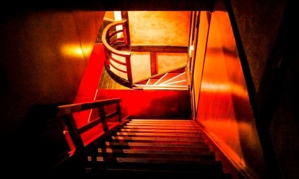 3階から2階へ下りる階段。赤いカーペットと丸い手摺りが特徴