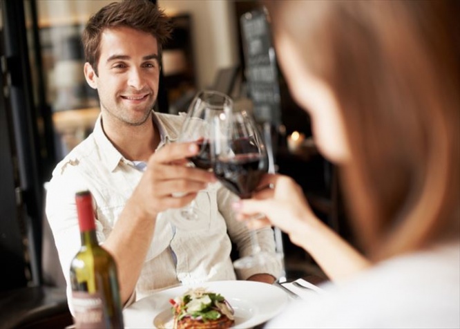 Smiling young man clinking glasses with his girlfriend while at dinner