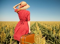 Redhead girl with suitcase at corn field.