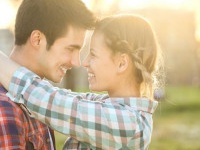 Happy attractive heterosexual couple embracing in a park. Both Caucasian in casual clothing, about 20-25 years old