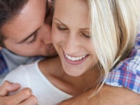 An affectionate man kissing his smiling girlfriends neck