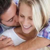 An affectionate man kissing his smiling girlfriends neck