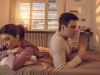 Young depressed couple being angry with each other and lying back to back on the bed.