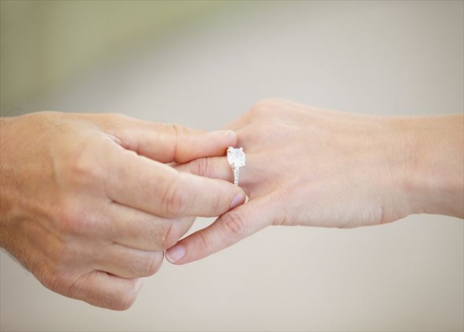 Cropped view of a man's hand sliding a wedding ring onto a woman's ring finger