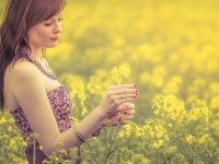 Attractive genuine young girl enjoying the warm summer sun in a wide green and yellow meadow. Part of series.