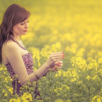 Attractive genuine young girl enjoying the warm summer sun in a wide green and yellow meadow. Part of series.