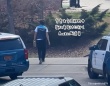 大捜査網。警察が大勢で建物を取り囲んでいる中、さらっと荷物を届けに行くAmazonの配達員