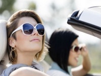 Close up of girls wearing sunglasses in the white car. Little holiday trip of friends