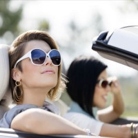 Close up of girls wearing sunglasses in the white car. Little holiday trip of friends