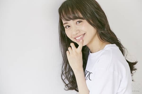 口に指をあててほほ笑む女性