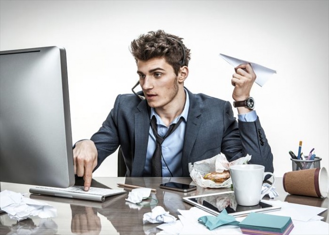 Guy with paper plane in his hand typing on a computer keyboard / modern office man at working place, sloth and laziness concept