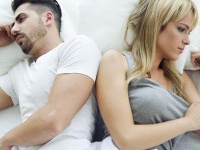 Portrait of upset couple lying back to back in bed