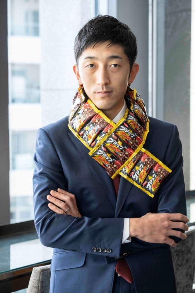 ブラックサンダーを首に巻いている河合辰信氏（有楽製菓提供）