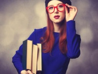 Portrait of beautiful girl in blue dress with books and bokeh on background.