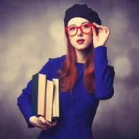 Portrait of beautiful girl in blue dress with books and bokeh on background.