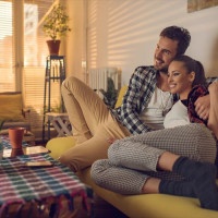 Happy couple sitting embraced in the living room and enjoying in their time together.