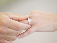 Cropped view of a man's hand sliding a wedding ring onto a woman's ring finger