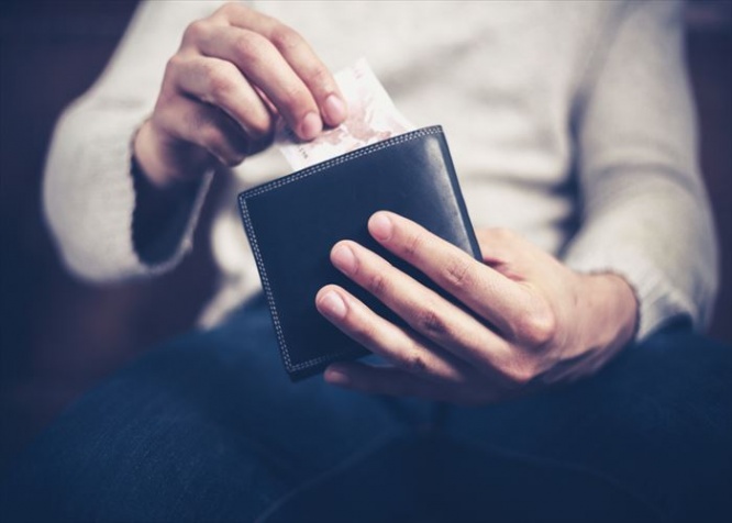 Closeup on a man's hands as he is getting a banknote out of his wallet