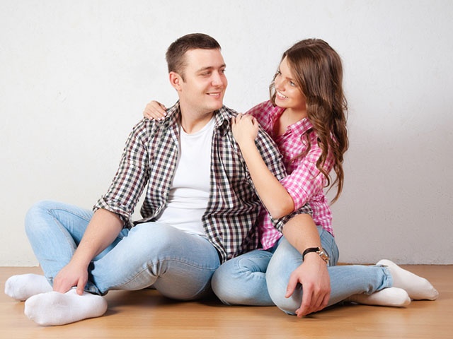 Portrait Of Happy Young Couple Sitting On Floor