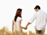 Rear view of a romantic young couple walking in a corn field