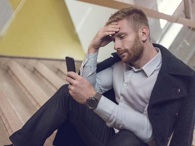 Worried businessman reading a text message on cell phone.