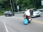 危険運転。二人乗りのバイク乗りがスーツケースを引きずって走行！