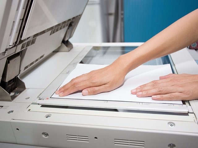 hands putting a sheet of paper into a copying device