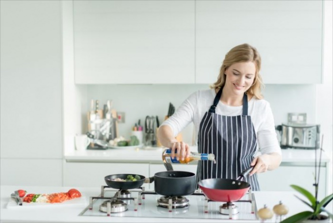 Happy woman cooking at home wearing an apron - healthy eating concepts