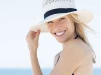 Woman wearing a straw hat and smiling. Portrait of a happy young woman in blue bikini with panama hat looking at camera with copy space.