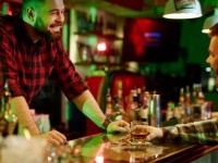 Happy barman talking to client in bar