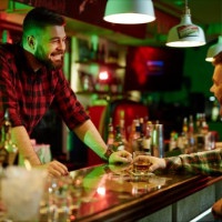 Happy barman talking to client in bar