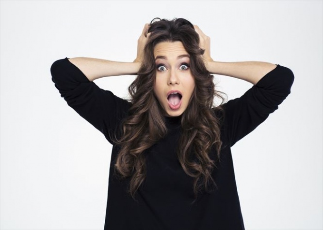 Portrait of a shocked woman with mouth open standing isolated on a white background