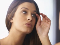 Shot of a woman looking at her appearance in the mirror