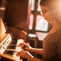 Young female pianist enjoying while practicing on retro styled piano.