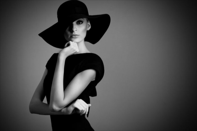high fashion portrait of elegant woman in black and white hat and dress. Studio shot