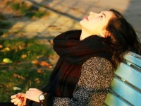 Girl sitting on the bench in the autumn in park