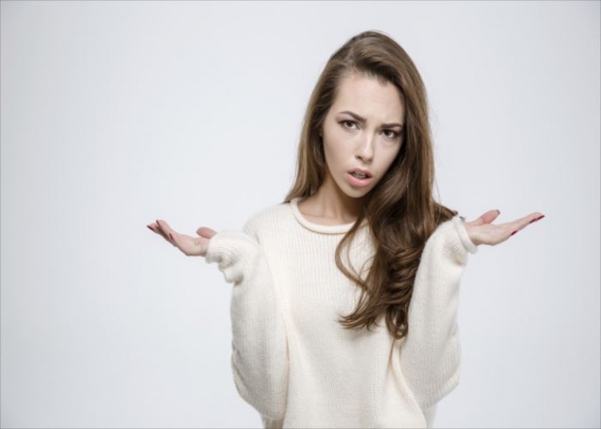 Portrait of a young casual woman shrugging shoulders isolated on a white background
